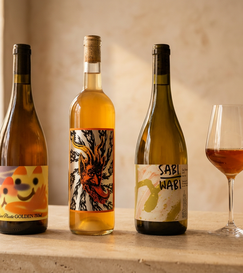 Italian Plastic Golden, Doom Juice Skins and Sabi Wabi Sugi Semillon bottles with a glass of amber wine on a sunlit bar.